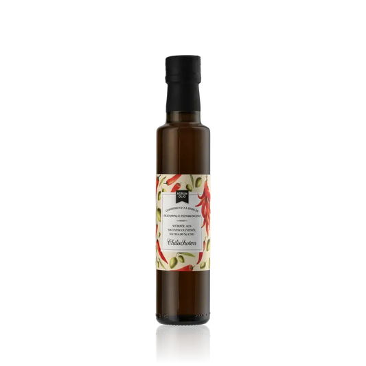 Flasche Agrumolio Olivenöl mit Chilischoten auf schwarzem Hintergrund.