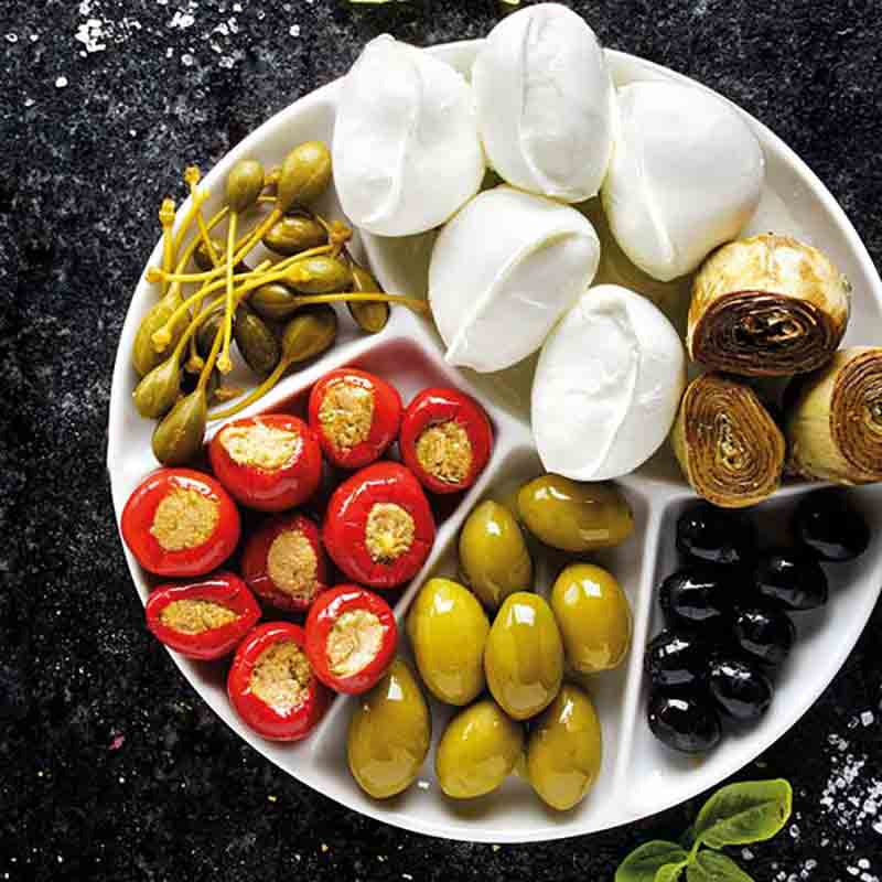 Antipasti-Teller mit Oliven, Mozzarella, gefüllten Paprika, Artischocken.