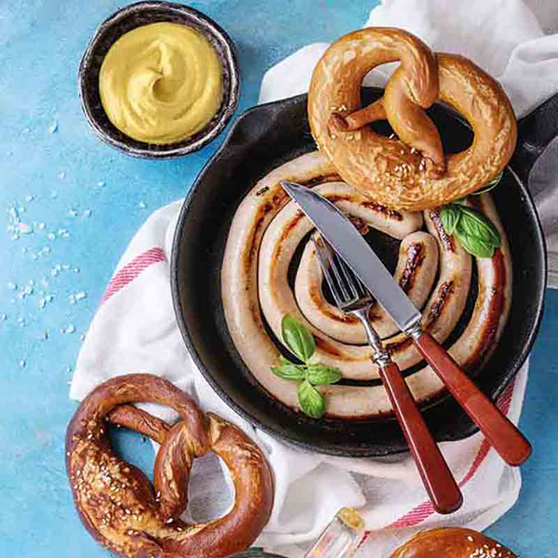 Bratwurst, Brezeln, Senf, Messer, Gabel, Pfanne, blaues Tuch.