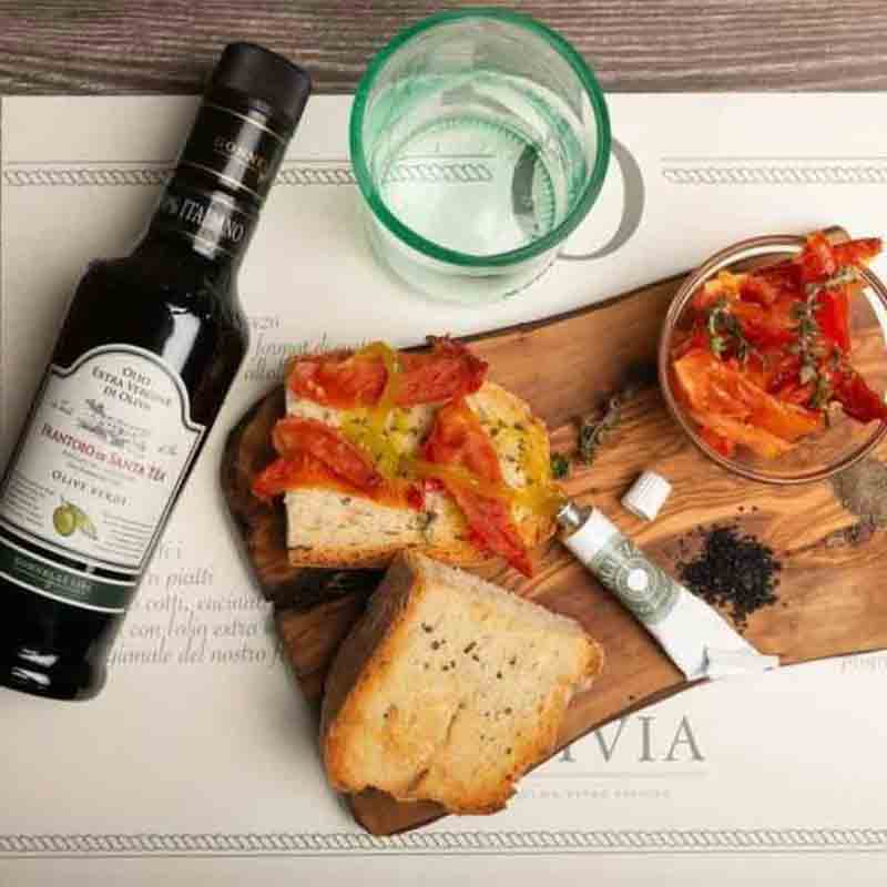 Olivenöl, Brot, Tomaten, Glas Wasser, Messer, Holzbrett.
