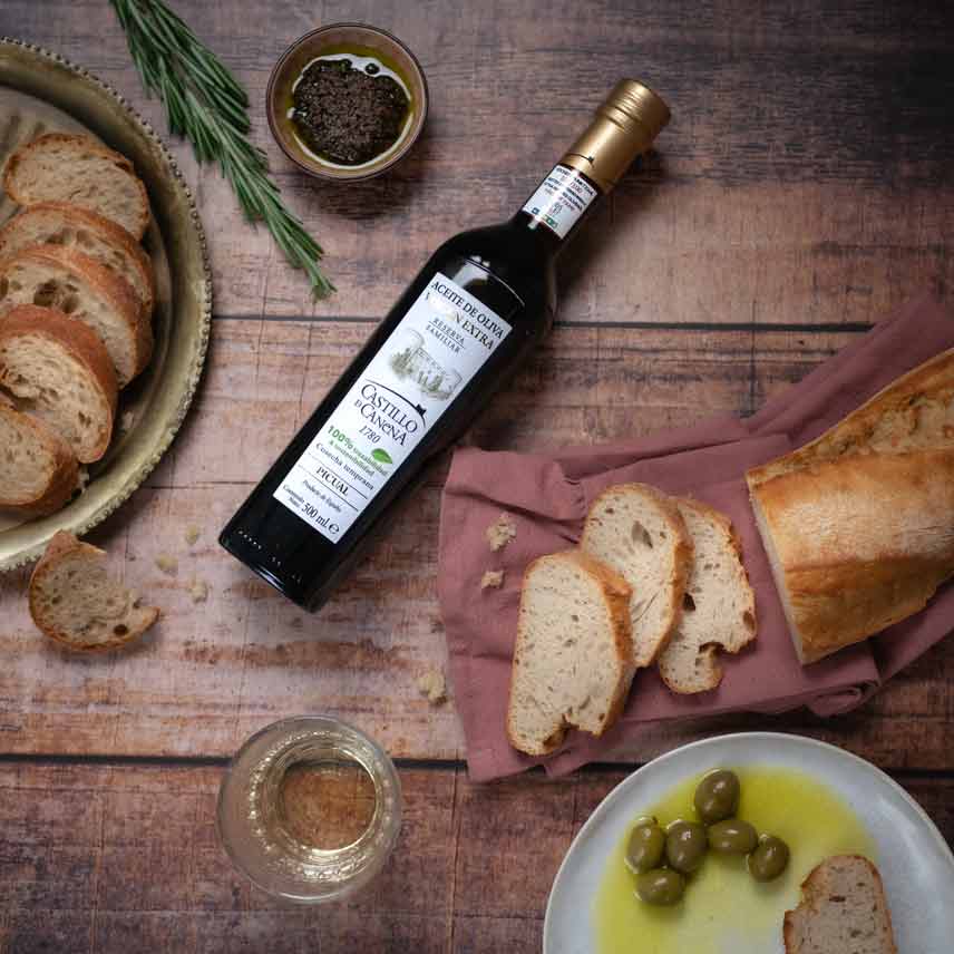 Brot, Olivenöl, Oliven, Wein, Rosmarin, Canena-Flasche, Teller, Tisch.