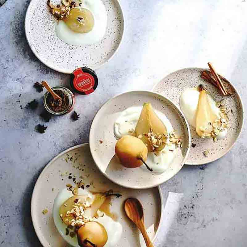 Dessertteller mit Birnen, Joghurt, Nüssen und Chai-Gewürz.