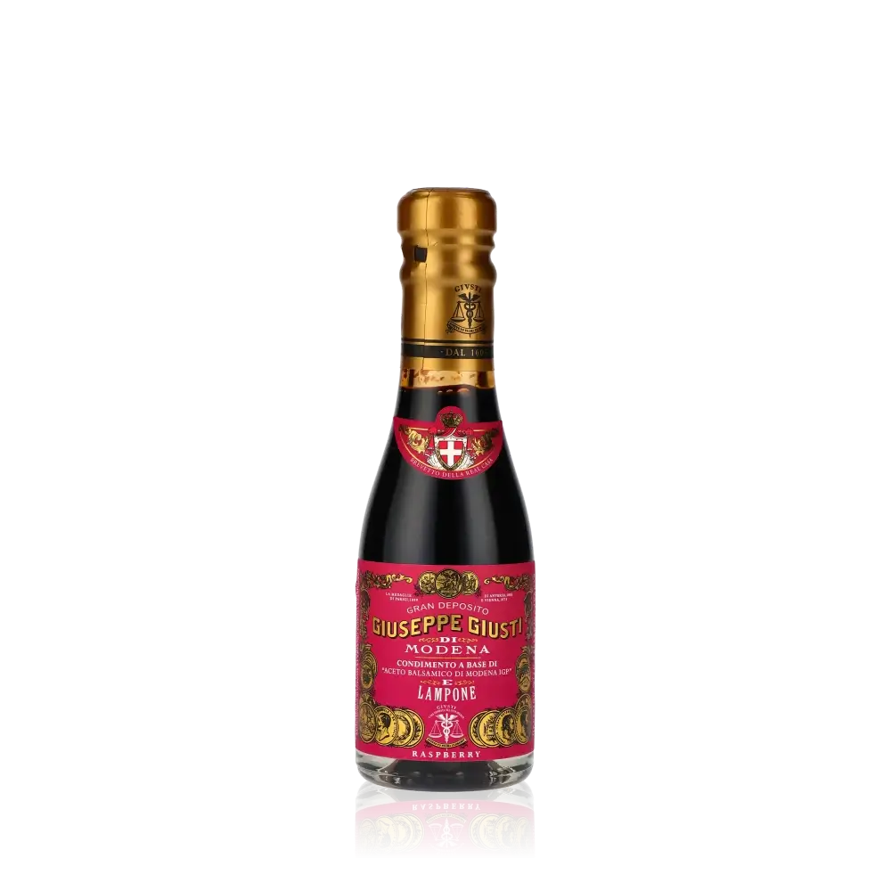 Giuseppe Giusti Himbeer-Balsamessig Flasche vor schwarzem Hintergrund.