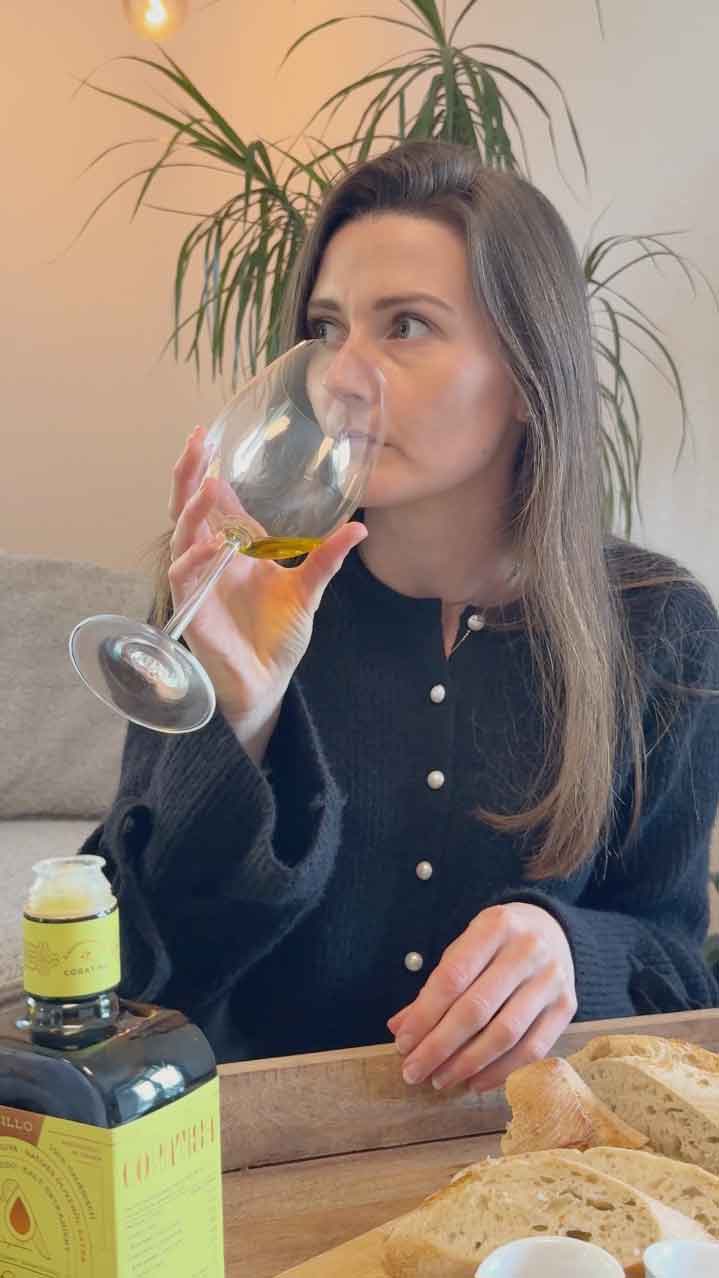 Frau riecht an Glas mit Olivenöl