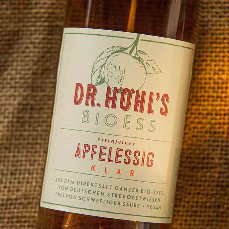 Dr. Höhl's Bioess Apfelessig Flasche auf Holzhintergrund.