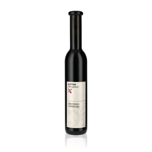 Flasche Acetum Manufaktur Himbeeressig vor schwarzem Hintergrund.