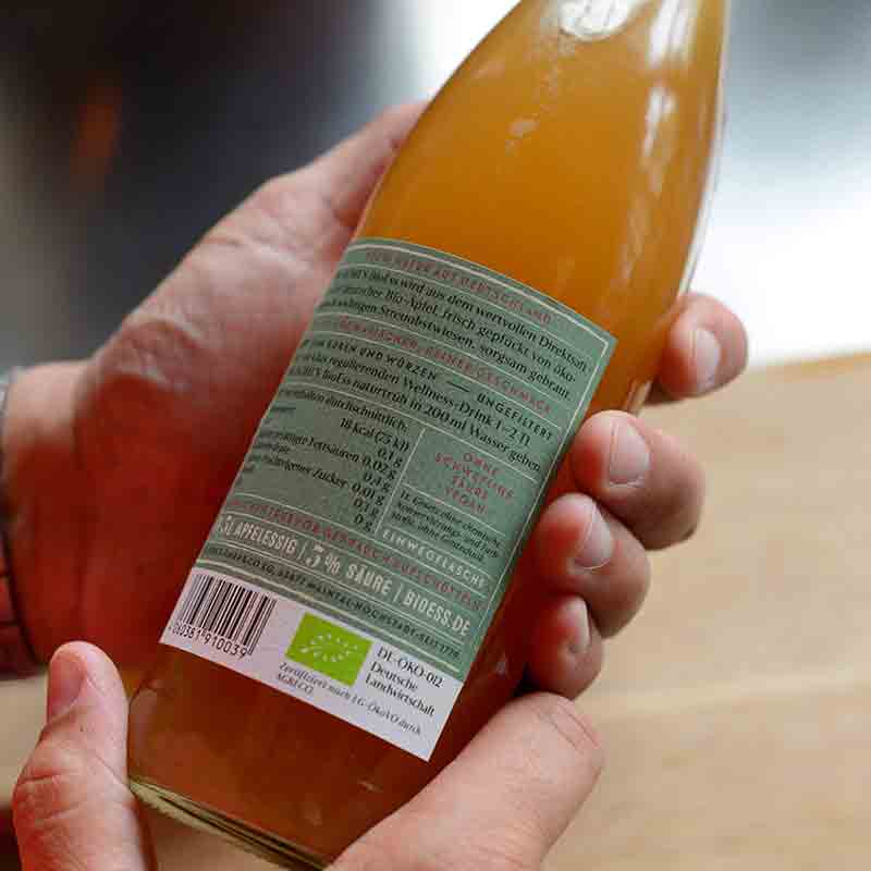 Person hält Flasche naturtrüben Bio-Apfelessigs von Dr. Höhl's.