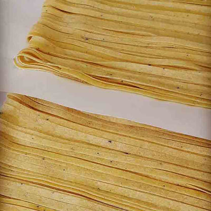 Trüffelpasta in Nahaufnahme, gelbe Nudeln mit schwarzen Punkten.