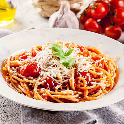 Spaghetti mit Tomatensauce, frischen Kirschtomaten und geriebenem Käse, garniert mit Basilikum.