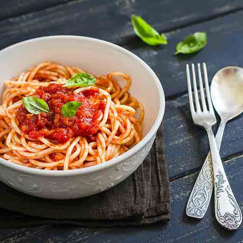 Eine weiße Schüssel mit Spaghetti und roter Sugo.