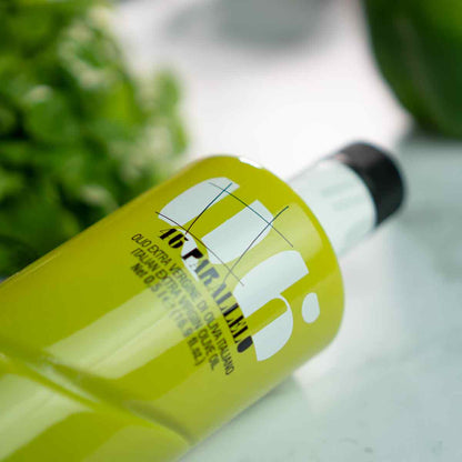Olivenölflasche Agraria Riva Garda auf Marmortisch liegend.