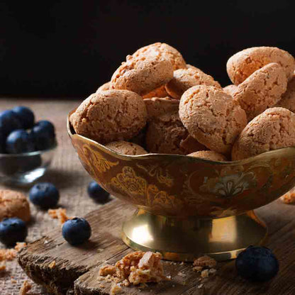 Amaretti-Kekse in Schale mit Heidelbeeren auf Holztisch.