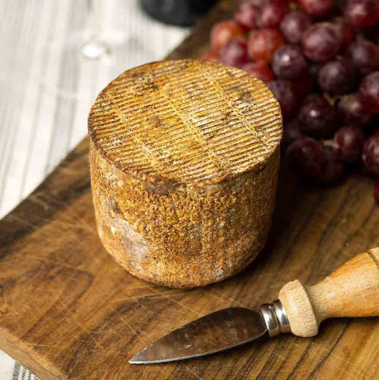 Käse, Trauben, Messer auf Holzbrett, rustikale Präsentation.