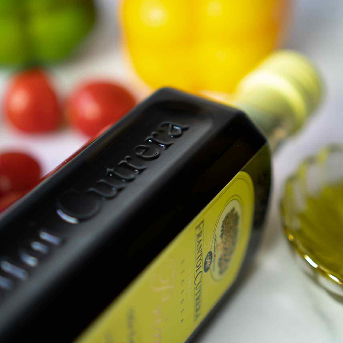 Flasche Olivenöl Cutrera mit Tomaten und Paprika.