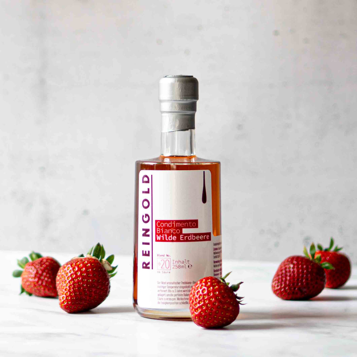 Reingold Erdbeerbalsamflasche mit frischen Erdbeeren auf Tisch.