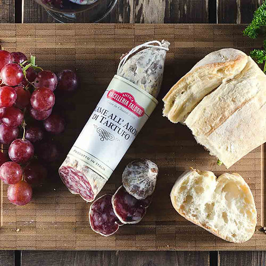 Trüffelsalami, Brot, Trauben auf Holzbrett, Falorni-Marke sichtbar.