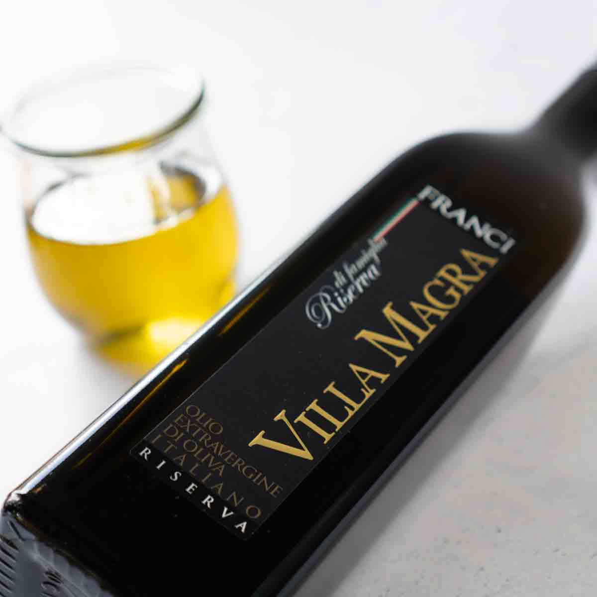 Franci Villa Magra Olivenölflasche und Glas mit Olivenöl.