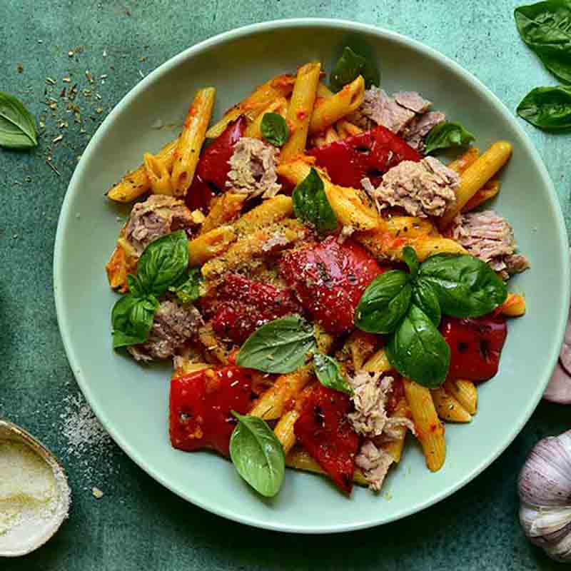 Pasta mit gegrillter Paprika, Basilikum und Thunfisch auf Teller.