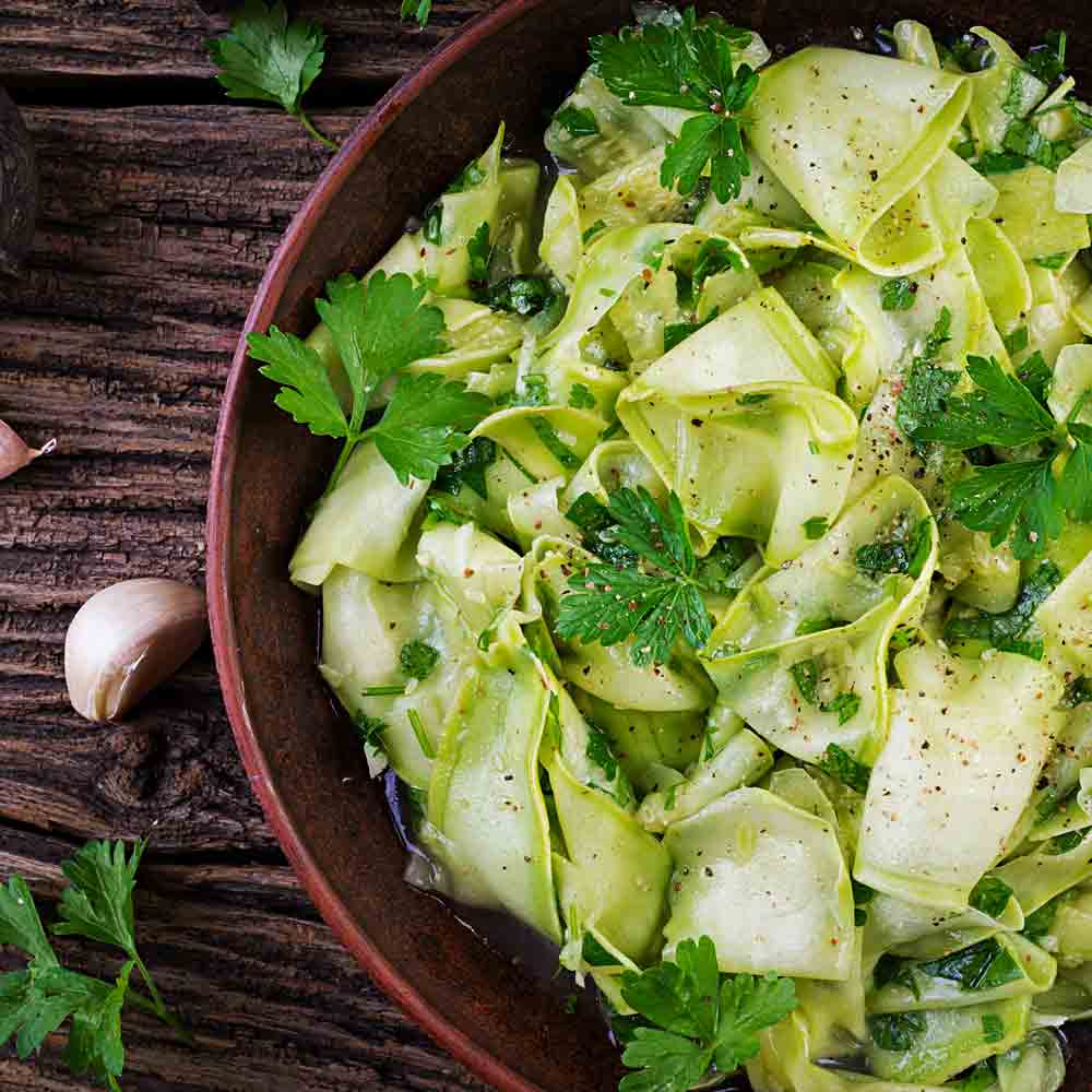Grüner Salat mit frischen Kräutern auf Holztisch angerichtet.