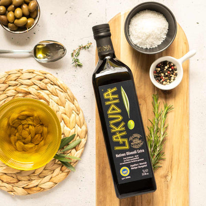 Lakudia Olivenölflasche mit Gewürzen und Oliven auf Tisch.