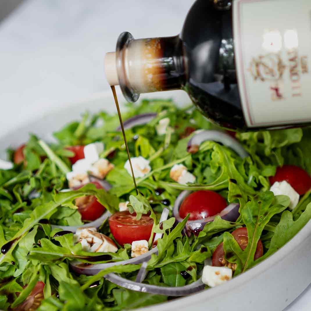 Balsamico-Essig von Leonardi wird über Salat gegossen.
