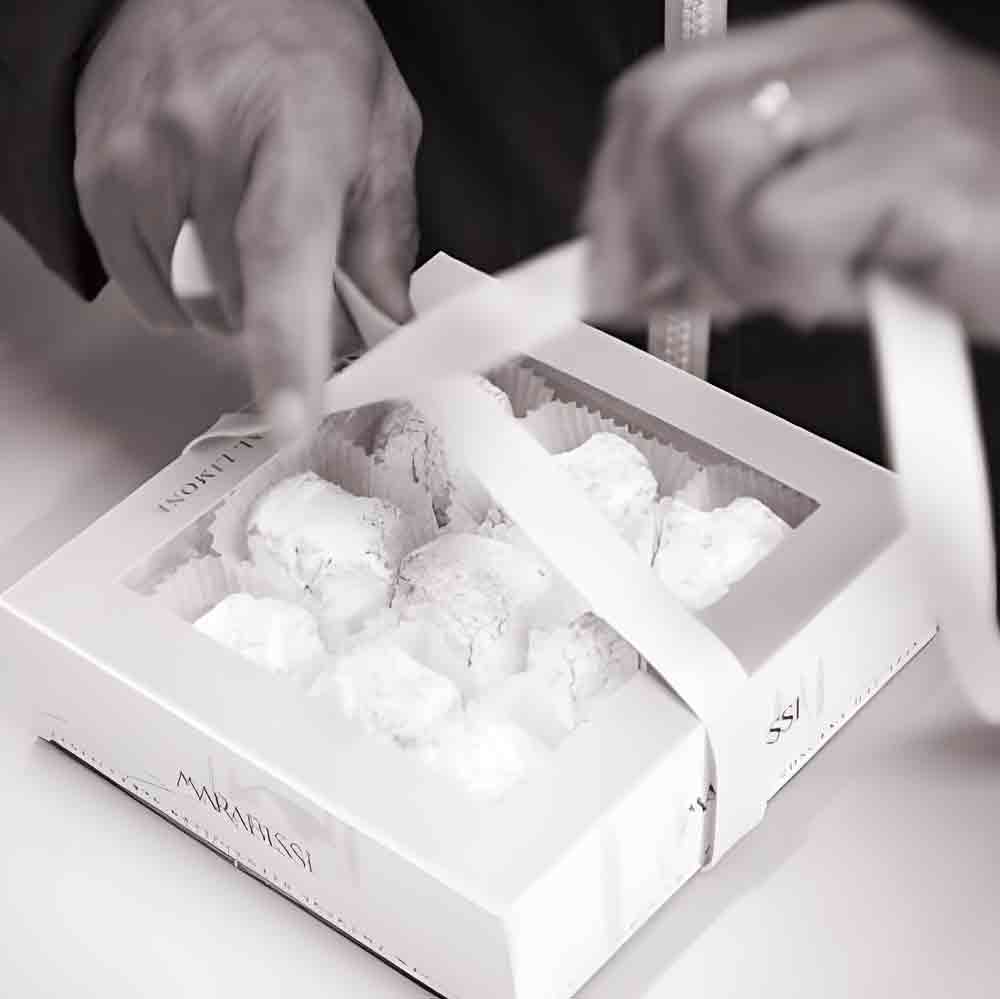 Person öffnet Marabissi-Geschenkbox mit Süßigkeiten.
