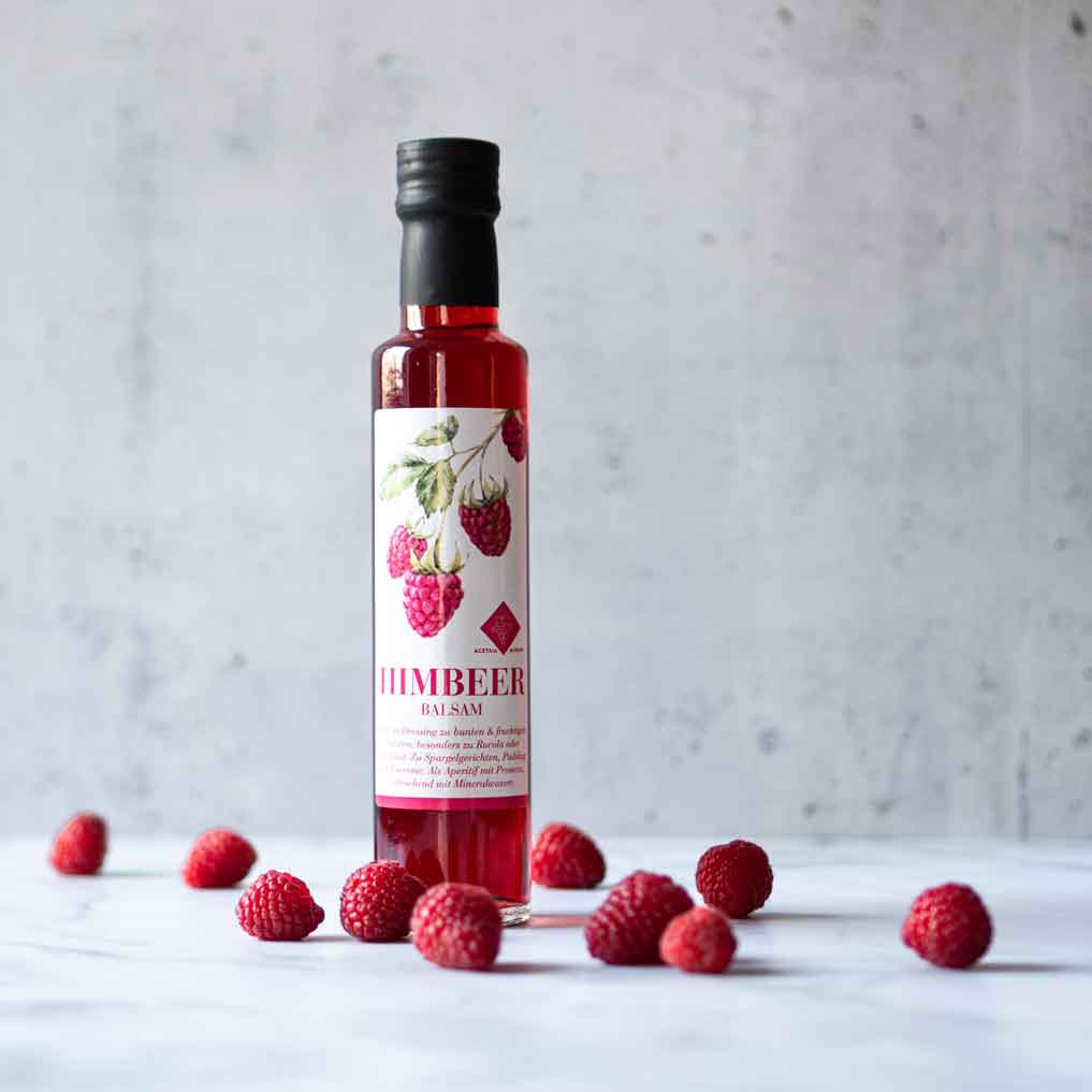 Murani Himbeerbalsam Flasche mit frischen Himbeeren auf Tisch.