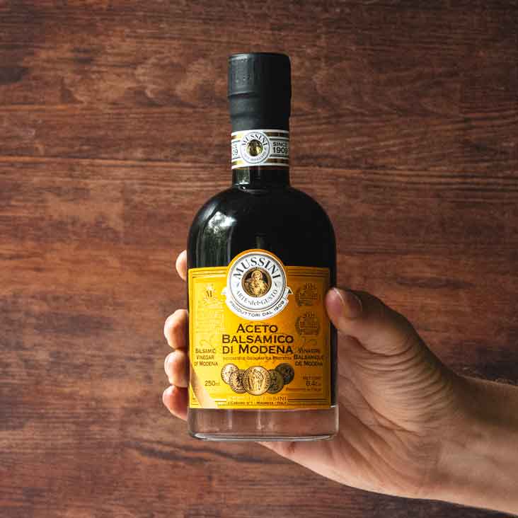 Hand hält Mussini Aceto Balsamico di Modena Flasche.