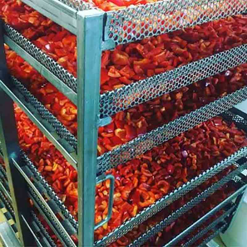 Geschnittene Paprika auf Metallregalen zur Trocknung gestapelt.