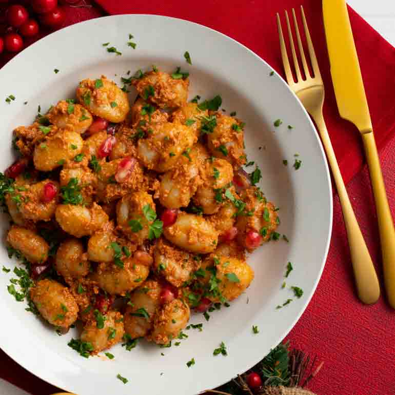 Gnocchi mit Pesto Rosso und Granatapfelkernen auf Teller.