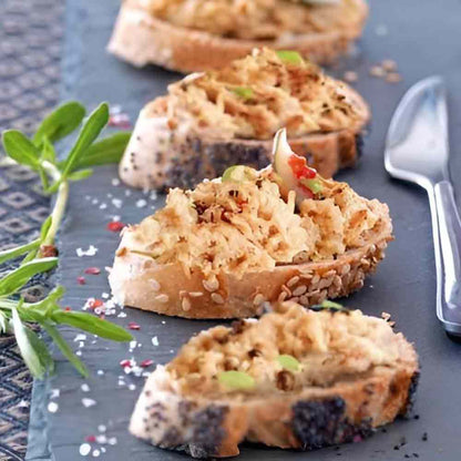 Brot mit Aufstrich auf Schieferplatte, dekoriert mit Kräutern.