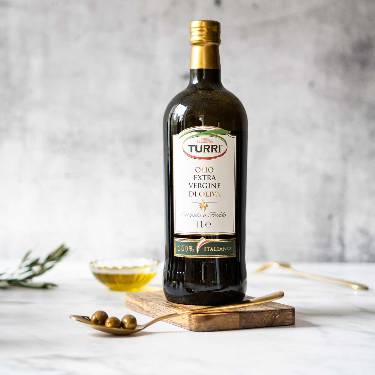 Flasche Turri Olivenöl auf Holzbrett mit Oliven.