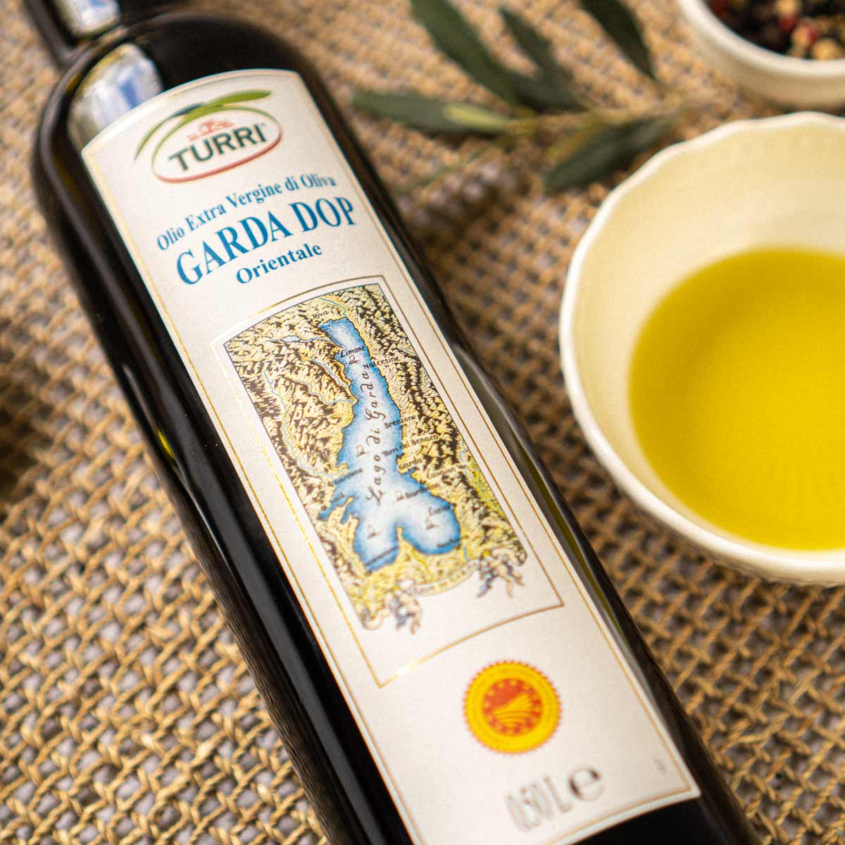 Turri Olivenölflasche mit Garda DOP Etikett auf Tisch.
