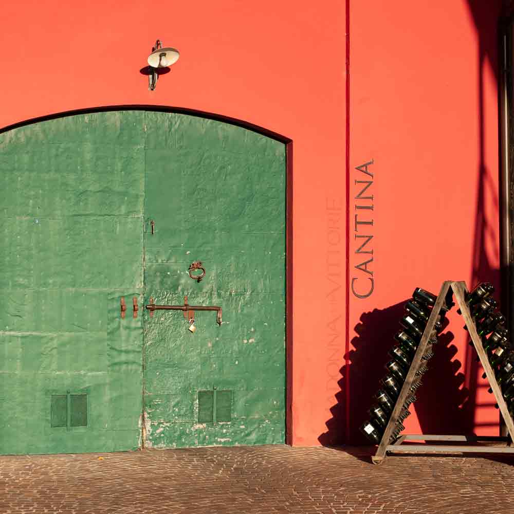 Grünes Tor, Weinflaschenständer, rote Wand, Cantina-Schriftzug.